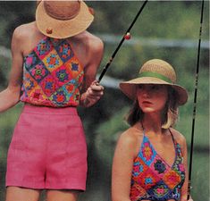 two women in swimsuits and hats standing next to each other holding fishing rods