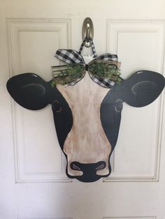 a cow head with a bow on it's head hanging from the front door