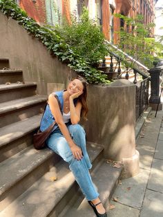 a woman is sitting on the steps in front of some stairs and smiling at the camera