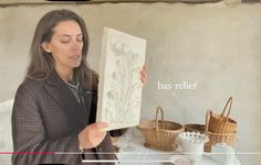 a woman holding up a piece of paper with the words bas relief in front of her