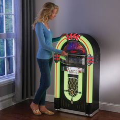 a woman standing next to a juke machine