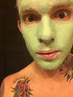 a man with green facial mask looking at the camera