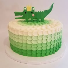 a cake with green and white icing that has a crocodile on top of it