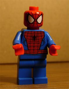 a lego spider - man is standing on a wooden table