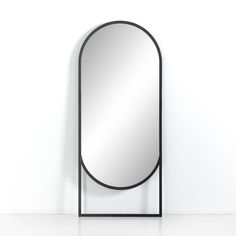 an oval mirror sitting on top of a metal stand