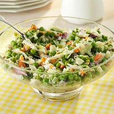 a salad with peas, carrots and shredded cheese in a glass bowl