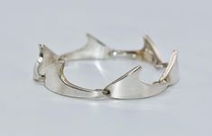 This stunning bracelet is a true vintage piece, handcrafted by the renowned Danish jewelry designer Bent Knudsen. Made of high-quality 925 sterling silver, it features a modernist style with a hook closure that makes it perfect for any occasion. The bracelet is 6-3/4 inches in length and has a unique link design. It is signed by the artist and is an original piece from the ca. 1960 era. The bracelet does not have any stones and is perfect for women who appreciate fine jewelry. It is a must-have for any collector of vintage and antique jewelry. The beautiful bracelet measures approx. 1/2 inch (12.7 mm) in width, weights 28.5 grams and is signed Sterling Denmark Bent K. Unique Formal Bracelets With Sterling Silver Clasp, Modernist Sterling Silver Oyster Bracelet For Formal Occasions, Modernist Sterling Silver Oyster Bracelet For Formal Events, Handmade Modernist Bracelet For Formal Occasions, Modernist Handmade Bracelet For Formal Occasions, Handmade Modernist Bracelets For Formal Occasions, Modernist Hallmarked Sterling Silver Bracelets, Modernist Hallmarked Sterling Silver Bracelet, Formal Hand-cast Metal Bracelets