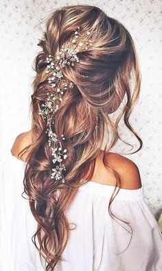 the back of a woman's head with long hair and flowers in her hair