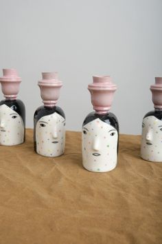 three ceramic heads with faces are lined up in front of each other on a table