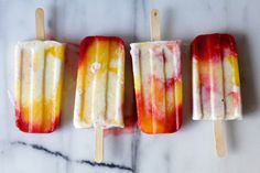 three popsicles are lined up on a marble surface