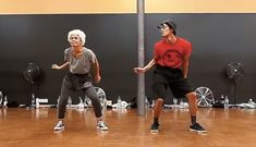 an older man and woman dancing on a wooden floor in front of a wall with mirrors