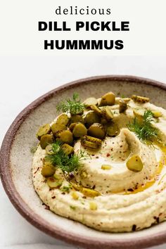 hummus in a bowl with dill pickles on top