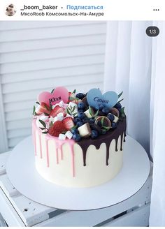 a white cake with chocolate icing and fruit on top is sitting on a table