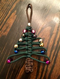 a christmas tree ornament made out of green string and colorful beads on a wooden table