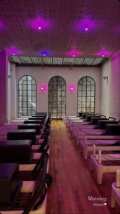 an empty room with rows of chairs and purple lighting on the ceiling is pictured in this image