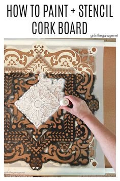 a person is painting an ornate design on a piece of cardboard with white paint and brown paper