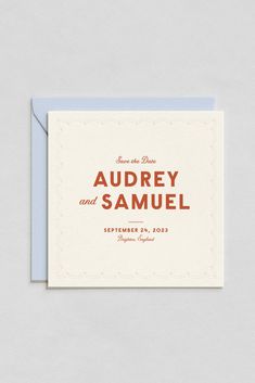 an orange and white save the date card on top of a blue envelope with red lettering