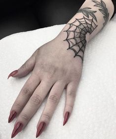 a woman's hand with a spider web tattoo on the middle of her arm