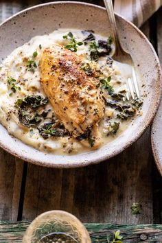 a white bowl filled with chicken and gravy on top of a wooden table