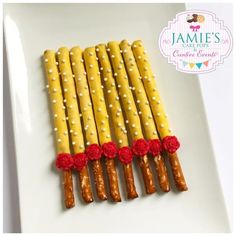 there are some yellow and white sticks with red flowers on them, sitting on a plate