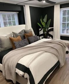 a bedroom with black walls, white bedding and wooden flooring is pictured in this image