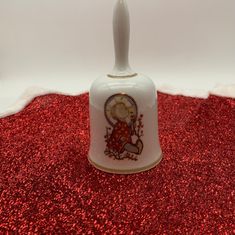 a small white bell with a bear on it's side and a red background