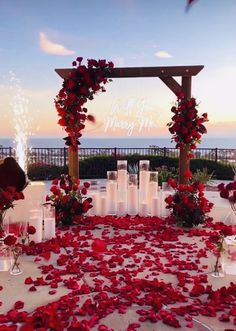 an outdoor wedding setup with red flowers and candles