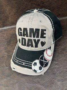 "PLEASE READ:     **FREE SHIPPING on orders of $35+ **This design ships in 3-4 days from the date the order is placed.   Please review all pictures and listing details/options here: STANDARD DESIGN DESCRIPTION: **Black and light grey two-tone adjustable ball cap. **Glitter GAME DAY with hearts on either side **Add up to 6 sports on the bill of the hat **Back of hat has a love heart.  Rhinestones embellish the adjustable closure. ** Up to 6 sports on the bill.  You let me know your sports in the notes at checkout ** On 1 or 2 or 3 sport designs, MOM or a name up to 6 characters will fit on the other side of the bill OPTIONS YOU CHOOSE AT CHECKOUT: Personalization/Customization:   ** No personalization **Name on back of hat.  See below ⬇️ **NAME ON BACK feature is extra $2-$7.  There are 3 o Game Day Hat With Letter Print And Curved Brim, Adjustable Sports Fan Hat With Letter Print, Customizable Black Hats For Baseball Season, Curved Brim Hat With Letter Print For Game Day, Fun Cap For Game Day, Fun Personalized Baseball Cap, Adjustable Fun Hats For Sports Events, Adjustable Cap For Game Day, Customizable Casual Birthday Hats