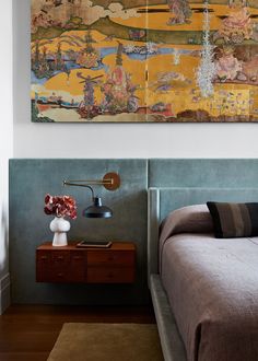 a bed sitting under a painting on top of a wooden dresser next to a lamp