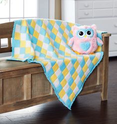 an owl blanket sitting on top of a wooden bench