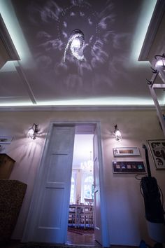 an open door leading to a room with pictures on the wall and lights above it