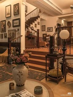 a living room filled with lots of furniture and pictures on the wall next to stairs