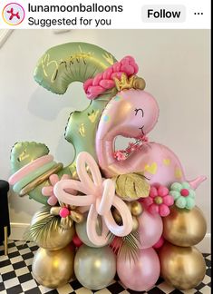 the balloon sculpture is pink, green and gold with an elephant on it's back