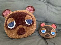 two crocheted teddy bears sitting on a couch next to each other, one with blue eyes