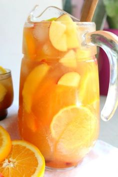 a pitcher filled with liquid next to sliced oranges