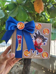 a person holding up a box with a blue ribbon around it and an image of gohan on the front