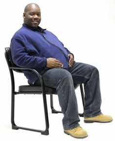 a man sitting in a chair with his hands on his hips and legs crossed, looking at the camera