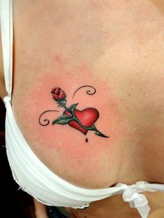 a woman's breast with a rose and heart tattoo on her left side shoulder