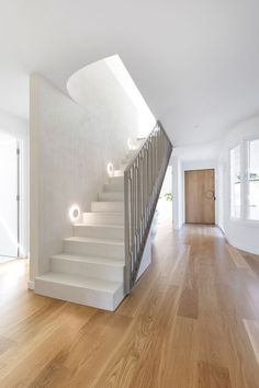 an empty room with white stairs and wooden floors