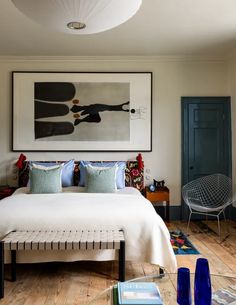 a bed sitting in a bedroom next to a painting