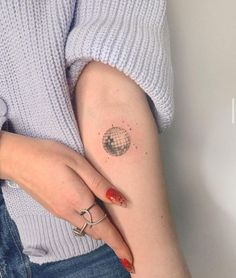 a woman's arm with a small globe tattoo on the left side of her right arm