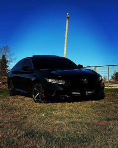 a black car parked on top of a grass covered field next to a tall pole