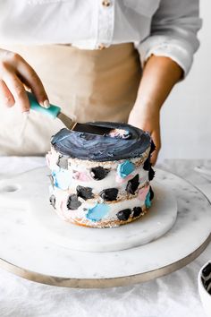 a woman is decorating a cake with blue icing