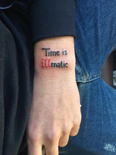 a person with a tattoo on their wrist that says time is illmote in red ink