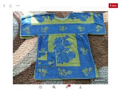 a blue and green flowered shirt laying on top of a carpet next to a rug