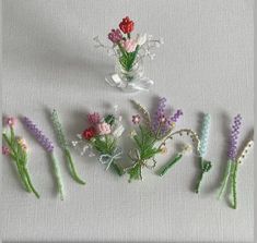 some flowers are sitting on a white table cloth and one is made out of beads