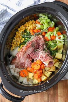 a slow cooker filled with meat, vegetables and corn is ready to be cooked