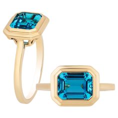 This London Blue Topaz Emerald Cut Bezel Set Ring in 18K Yellow Gold is a sleek piece from the 'Manhattan' Collection. It features a stunning emerald-cut London Blue Topaz stone set in a 18K yellow gold bezel. This ring embodies modern elegance, offering a touch of luxurious style. Its clean lines and rich hues make it a timeless accessory that effortlessly elevates any look, channeling the chic essence of Manhattan's cosmopolitan vibe. * Gemstone size: 9 x 7 mm * Gemstone: 100% Earth Mined * Approx. gemstone Weight: 3.08 Carats * Cut: Emerald * Metal: 18K Yellow Gold Luxury Emerald-cut Topaz Ring Timeless Style, Luxury Timeless Emerald Cut Topaz Ring, Luxury Timeless Emerald-cut Topaz Ring, Luxury Blue Topaz Ring With Bezel Setting, Luxury Emerald-cut Yellow Gold Topaz Ring, Goshwara Jewelry, Gold Topaz Ring, London Topaz Ring, Rock Rings