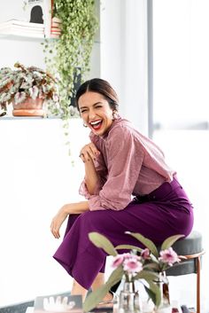 a woman sitting on top of a chair in front of a table filled with flowers