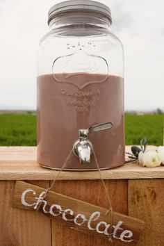 a glass jar filled with chocolate sitting on top of a wooden table next to a sign